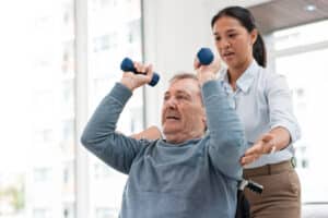 Cedar River Healthcare Center rehab tech helping resident with weights